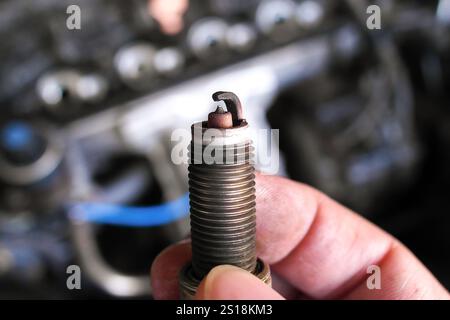 Close up of used spark plug in hand , car spark plug for engine ignition system , Automotive parts concept Stock Photo