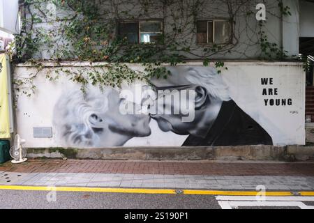 A black and white painting, poster, wall, street mural of two old people kissing. In Seoul, South Korea Stock Photo