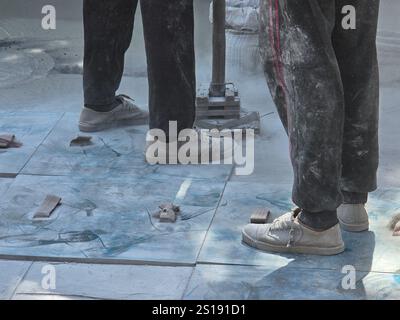 Workers skillfully apply stamp concrete methods in Pattaya Thailand, The atmosphere is filled with dust as they create beautiful patterns on the surface, showcasing craftsmanship. Stock Photo