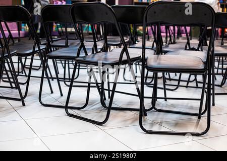 empty folding black chairs after conference in interior Stock Photo