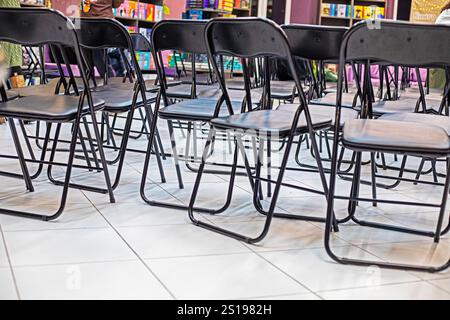 empty folding black chairs after conference in interior Stock Photo