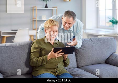 Senior happy couple at home, older man and woman having fun with computer tablet, elder Stock Photo