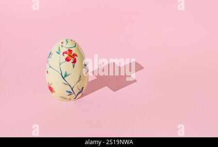 Easter egg with Christian cross shadow on pastel pink background. Minimal Easter concept. Creative festive spring holiday layout. Stock Photo
