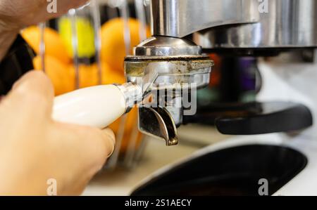 Close-up of a barista's hand fixing a portafilter onto a coffee machine. Stock Photo