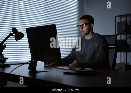 Programmer working on computer indoors at night Stock Photo