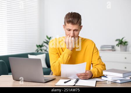 Tired student having stress before exam at table indoors Stock Photo