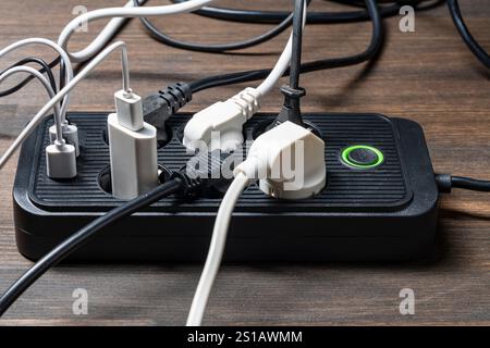 AC outlet multiprise power strip with USB plugs at home. Electrical plug in outlet socket at home. Energy efficiency concept. Black plastic power stri Stock Photo