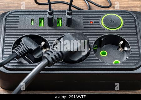 AC outlet multiprise power strip with USB plugs at home. Electrical plug in outlet socket at home. Energy efficiency concept. Black plastic power stri Stock Photo