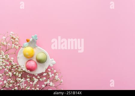 Spring Easter background, multi-colored Easter eggs in a decorative hen with gypsophila flowers on a pink background, copy space Stock Photo