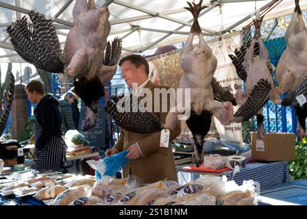 Free range turkeys hanging up being displayed for sale in market shop stall. Free range uk turkey farmer Jacob Sykes from Fosse Meadows Farm, at a London Farmers Market a regular Sunday weekly pitch.  Queens Park Farmers Market, North London  November 2012 2010s UK HOMER SYKES. Stock Photo