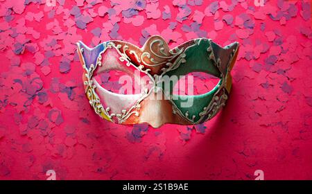 Carnival confetti festive background. Colorful mask and confetti on bright pink color background, top view Stock Photo