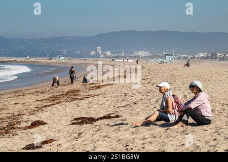 A couple of local residents cleanup trash and plastic on beach in Playa Del Rey that washed up the day after Tropical Storm Hilary hit Los Angeles. Au Stock Photo