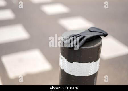 photo Black Leather Glove Resting on Metallic Bollard in Urban Crosswalk Setting Creates Sense of Mystery and Intrigue in Everyday Cityscape Encounter Stock Photo