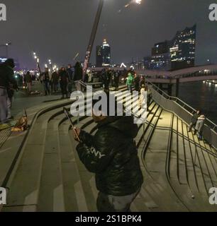 Person launches firework rocket from his hand, New Year's Eve 2025 on the Elbe promenade in Hamburg, at the harbour, on the Elbe, fire brigade of many Stock Photo