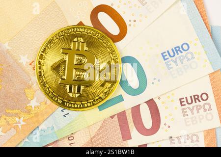 cryptocurrency, a coin representing Bitcoin on several euro notes, close-up Stock Photo