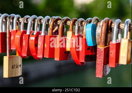 Close up details of many locks hanging on a bridge under the sun, reprenting true love of many couples Stock Photo
