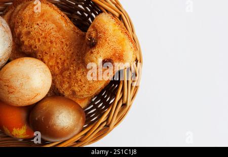 Small Easter lamb cake and painted eggs in a wicker basket on white background. Simple Easter flat lay in neutral colors with copy space Stock Photo