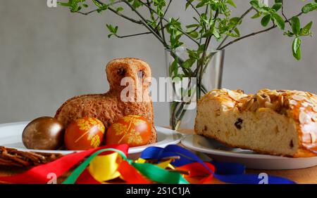 Easter still life containing a small lamb cake, painted eggs, traditional Czech Easter sweet cake called "mazanec", an Easter whip and green twigs in Stock Photo
