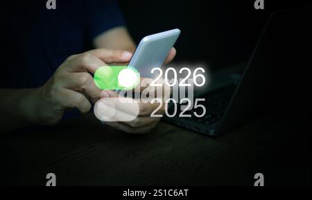 Happy new year 2026. A man, with a smartphone, taps on-switch of 2026 toggle button to start and welcome the new coming year. Stock Photo