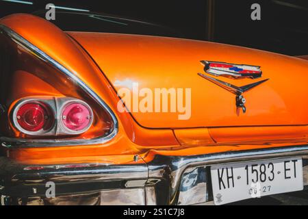 Balikpapan, Indonesia - December 18th, 2024. A close-up view of the rear of a vintage orange car, showcasing its chrome details, taillights, and Chevr Stock Photo