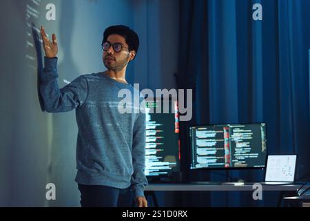 Indian man programmer standing in front of a screen with code projected  presentation the integration of technology and human expertise in software de Stock Photo