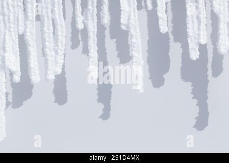 Row of white sunlit snow icicles and shadows Stock Photo