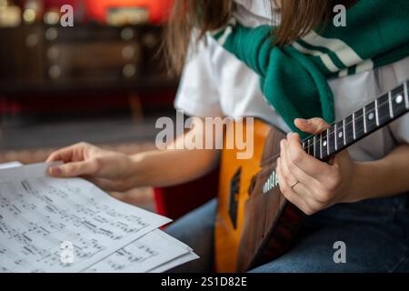 Female music student examines balalaika notes and chords, planning practice session at home or class Stock Photo