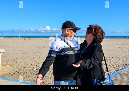 Happy retired couple spending time together on a sunny beach, enjoying their leisure time Stock Photo