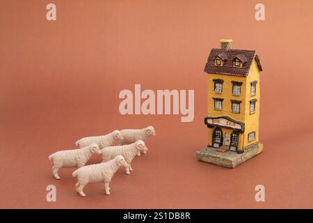 Miniature building sculpture model with sheep on brown background Stock Photo
