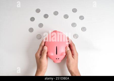 Hand holding piggy bank isolated on white background. Top view. Saving money for retirement fund and future planning concept. Stock Photo