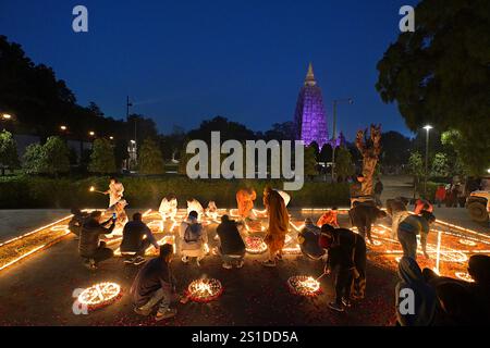 People celebrating the New Year 2025 and lighting candles at the Butter Lamp House, with the Mahabodhi Temple illuminated in purple, Bodhgaya, India Stock Photo
