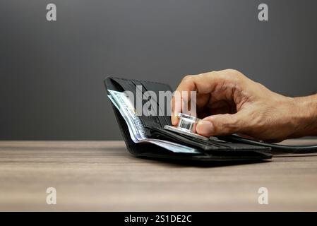 A hand holds a stethoscope over an open wallet with money inside, symbolizing the concept of financial health and status. Stock Photo