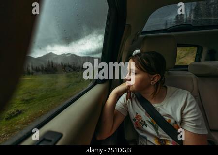 Girl riding in car looking out rainy window Stock Photo