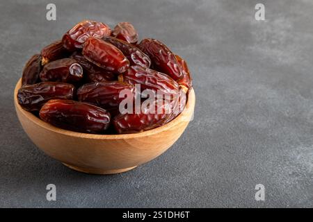 Large dates fruit in a wooden bowl, top view Stock Photo