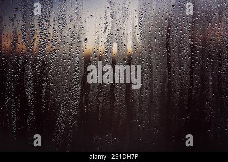 Raindrops on a window with sunset sky Stock Photo