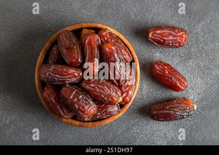 Large dates fruit in a wooden bowl, top view Stock Photo