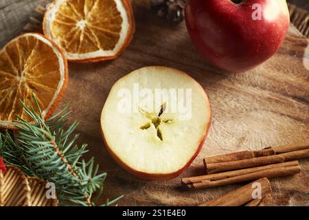 Halved apple with a star in the middle, with cinnamon, dried orange slices and Christmas decoration Stock Photo