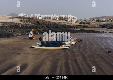 Canary Island, Tenerife-December14,2023.surfers going for surfing in the ocean.Coach show how to surf to the group. High quality photo Stock Photo