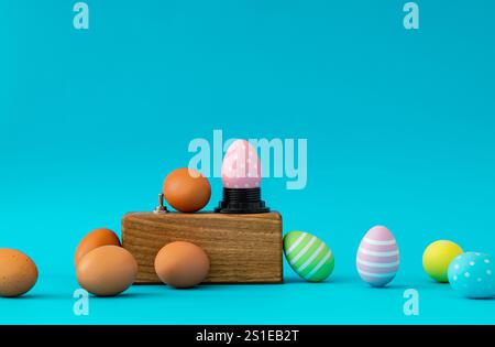 Colorful eggs and magical Easter eggs coloring machine on light blue background. Minimal Easter surreal concept. Creative festive holiday layout. Stock Photo