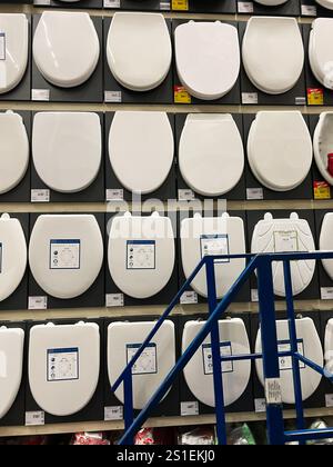 Kyiv, Ukraine - January 03, 2025: Various types of white toilet seats displayed on a wall in a home improvement store, showcasing different styles and Stock Photo