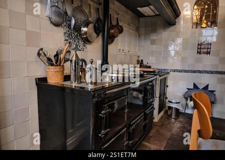 A historic Dutch kitchen featuring a vintage stove, hanging utensils, and tiled walls. A perfect blend of heritage and rustic charm. Stock Photo