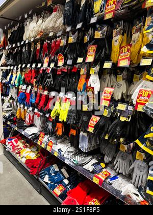 Kyiv, Ukraine - January 03, 2025: A variety of work gloves in multiple colors and styles displayed on store shelves with marked discounts, designed fo Stock Photo