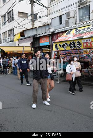 Young Couple Taking Photos of Their Food at Tsujiki Outer Market in Tokyo Japan Stock Photo