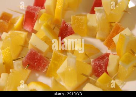 Bright and refreshing fruit skewers are arranged on a plate, perfect for a sunny outdoor event. Ideal for summer picnics or parties. Stock Photo