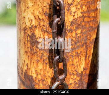 Rusty old chain and lock hanging on a rusted pole Stock Photo