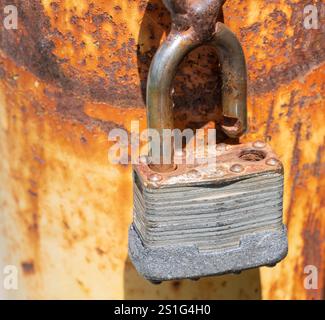 Rusty old chain and lock hanging on a rusted pole Stock Photo