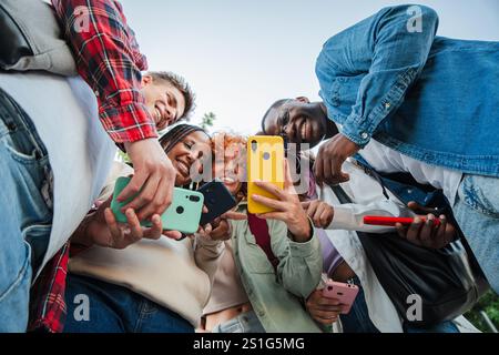 A joyful group of diverse student friends smiling while interacting with their cellphones, capturing moments, sharing laughter, and bonding through technology, emphasizing connection and friendship. High quality photo Stock Photo