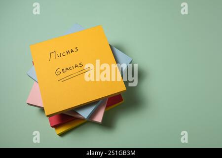 Yellow sticky note with "Thank you" message in Spanish on pastel background Stock Photo