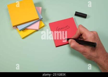Handwriting a heart on a red sticky note with "Gracias" message Stock Photo