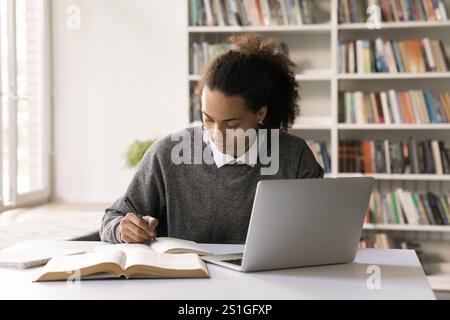 Focused male student work on project at library using notebook Stock Photo